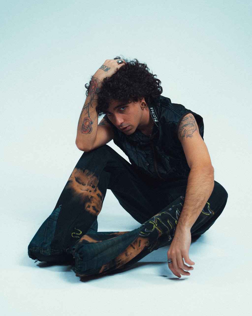 Klaus Noir su sfondo bianco seduto e con una mano in testa