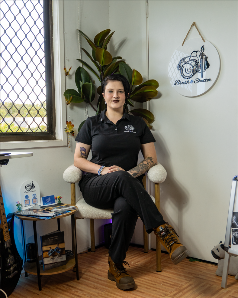 Professional female photographer sitting in her studio at Brush and Shutter with camera gear and art decor.