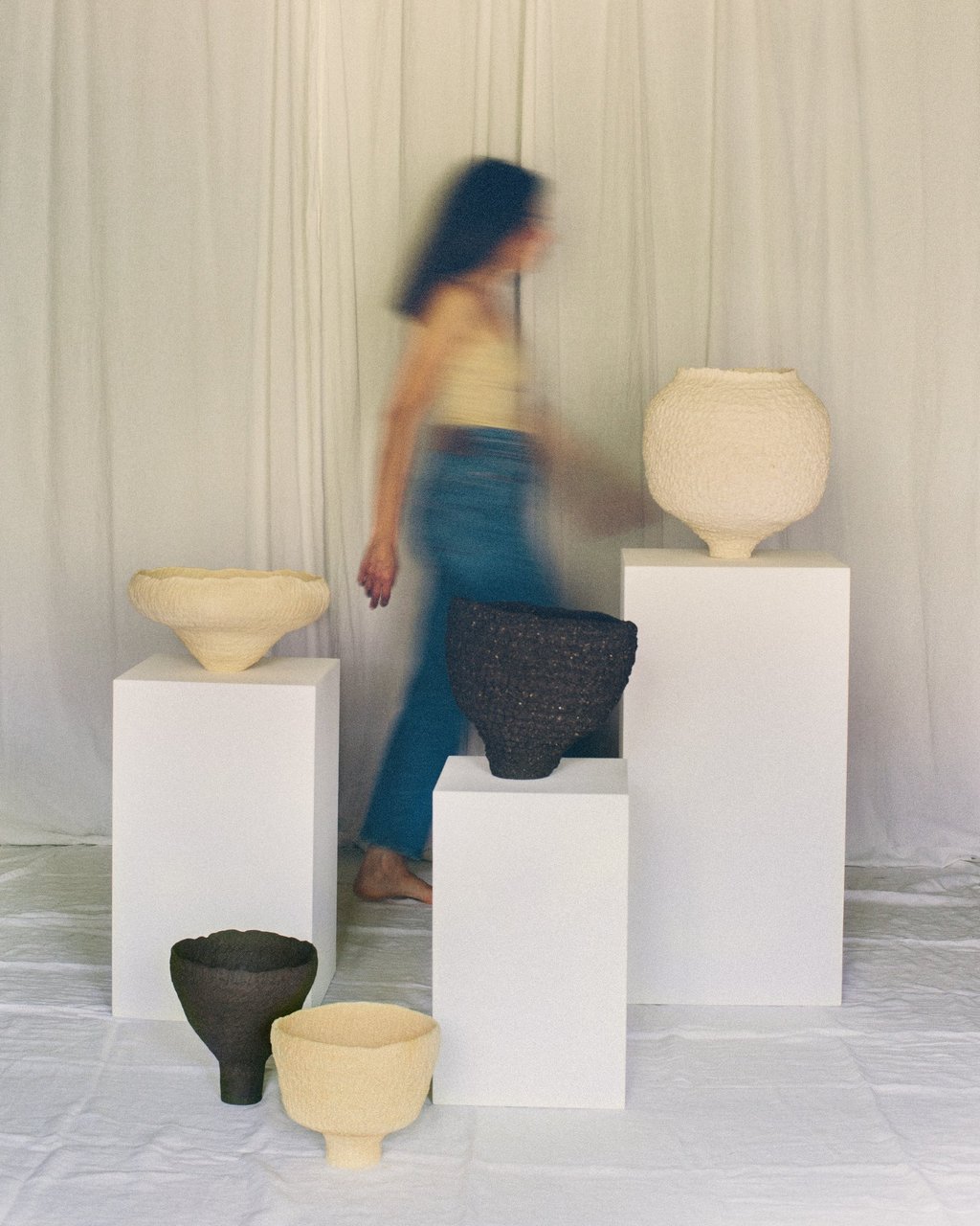 Sabine Segura marchant derrière les sculptures en grès de la série de céramiques Kairos