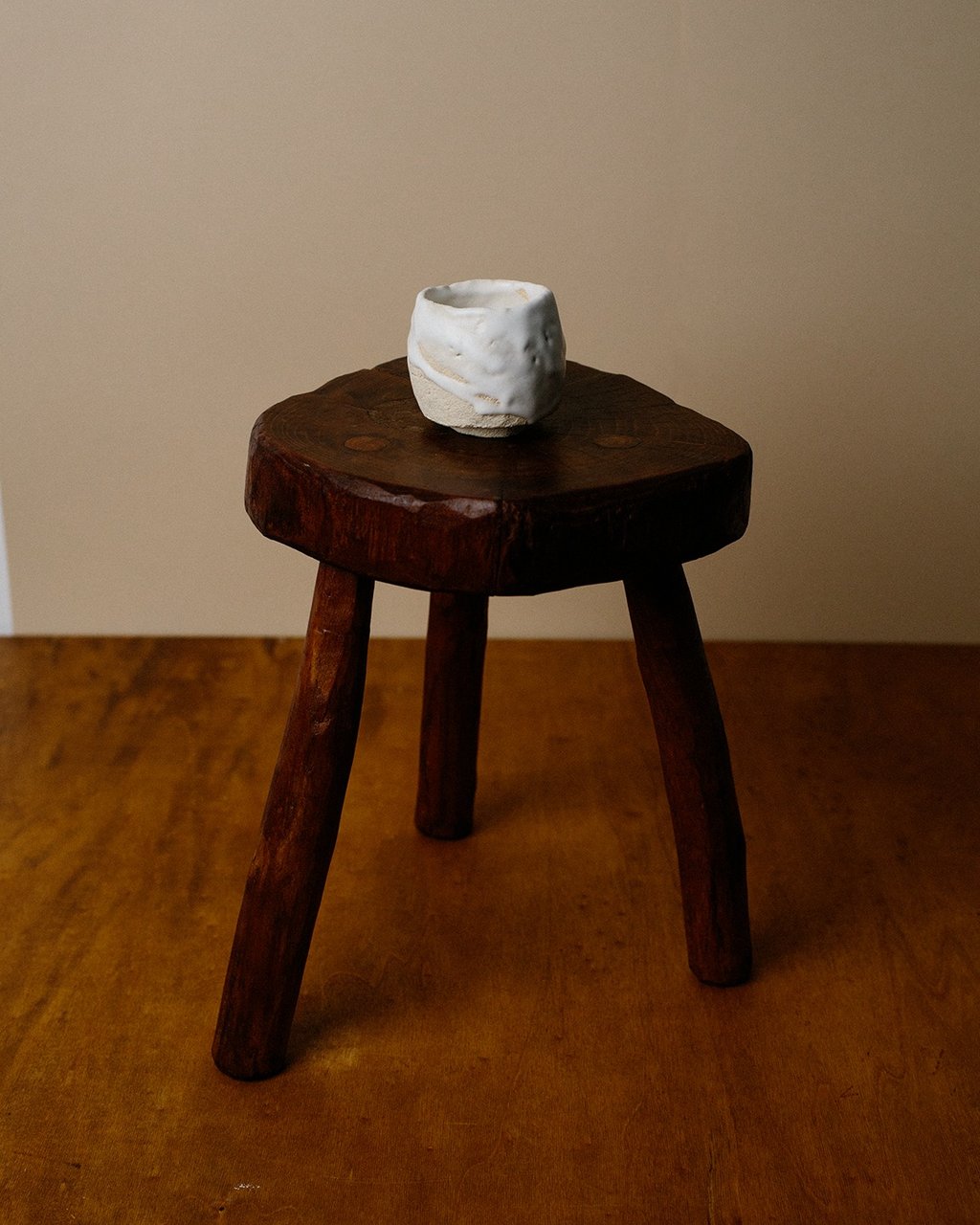 Tasse en grès blanc d'exception avec émail kudo-matto posé sur un tabouret en bois