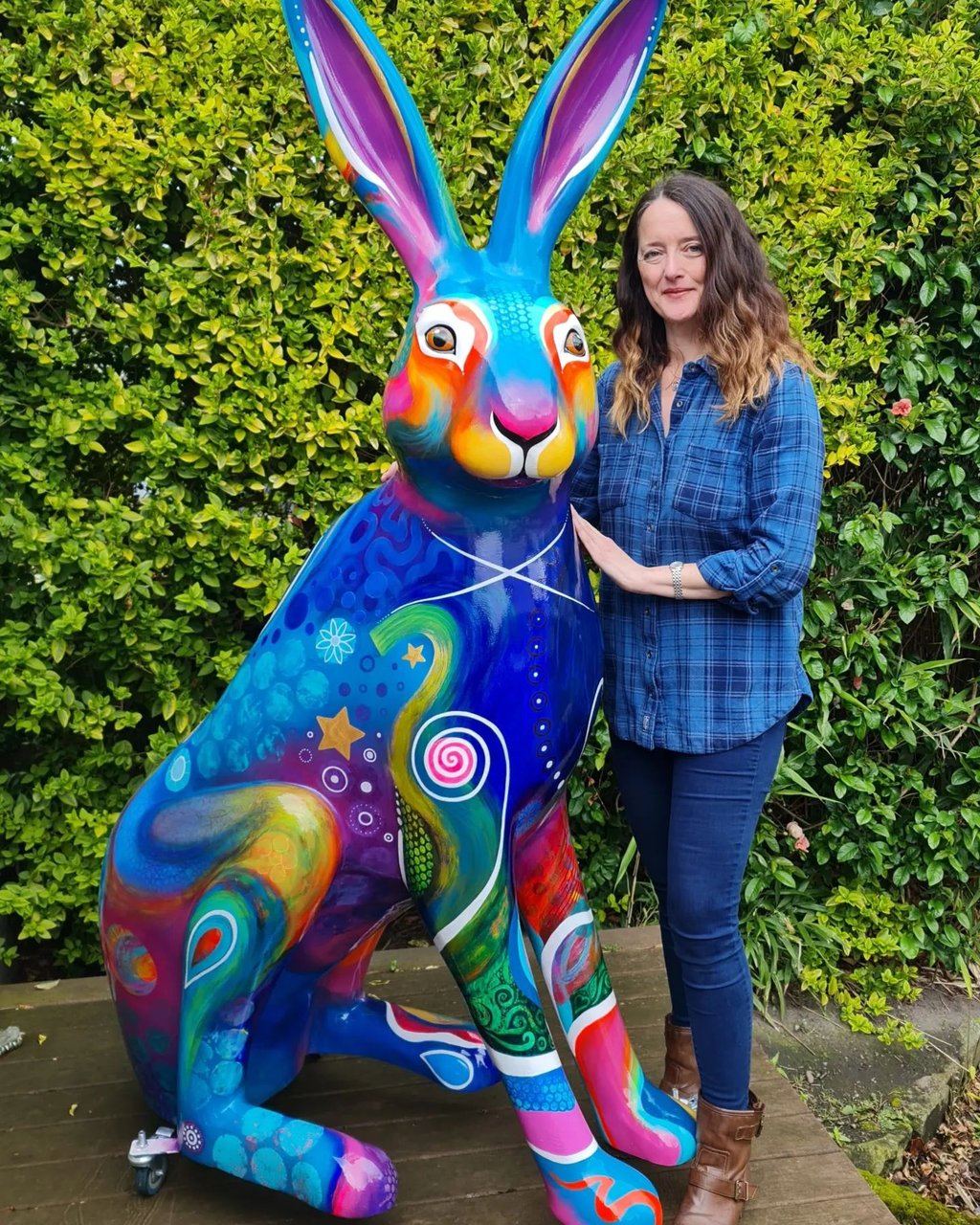 Alanda Calmus artist stands beside a large, brightly painted Big Hop Trail Hare sculpture