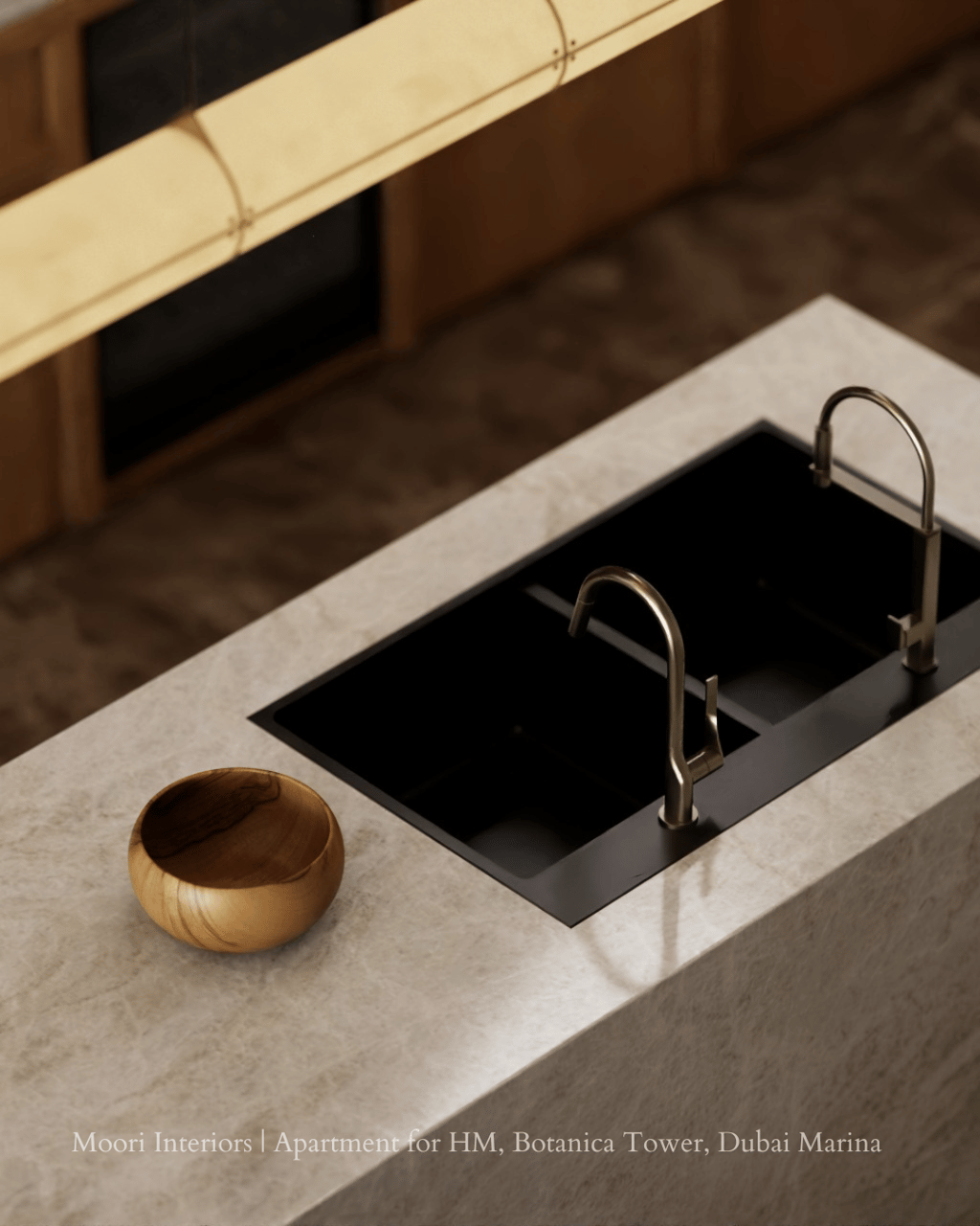 Black double sink integrated into a light-colored kitchen island, with two brass faucets.