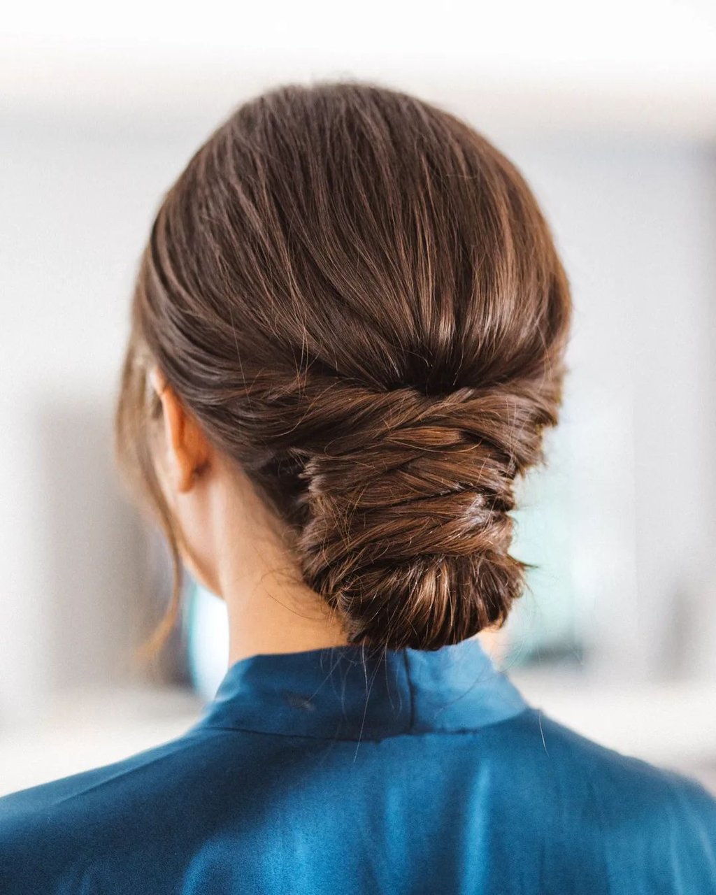 A bride wearing her hair in a low effortless bun with twists