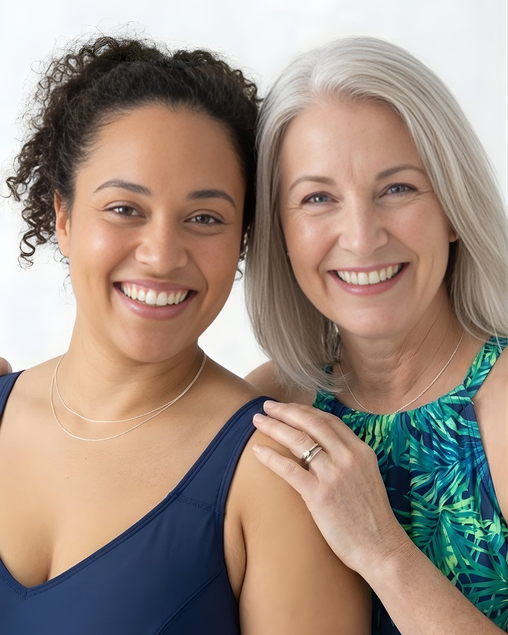 Two diverse smiling women of different ages posing together in summer fashion swimwear.