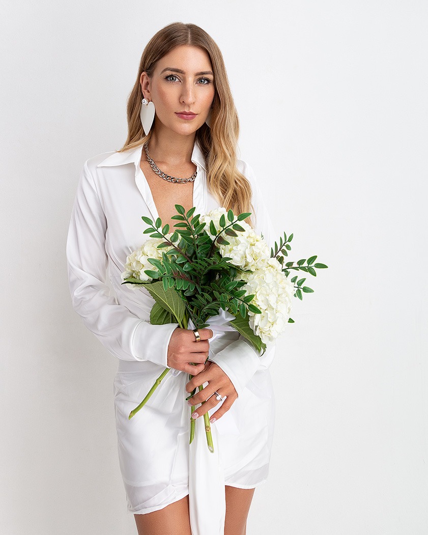 a woman in a white shirt and a necklace with flowers