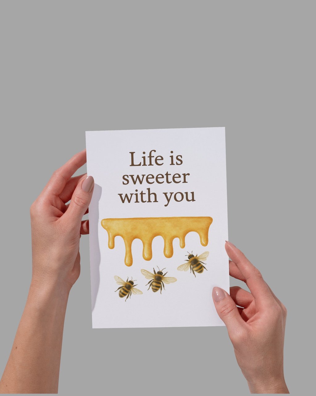 Hand holding a greeting card with dripping honey and bees that says Life is sweeter with you.