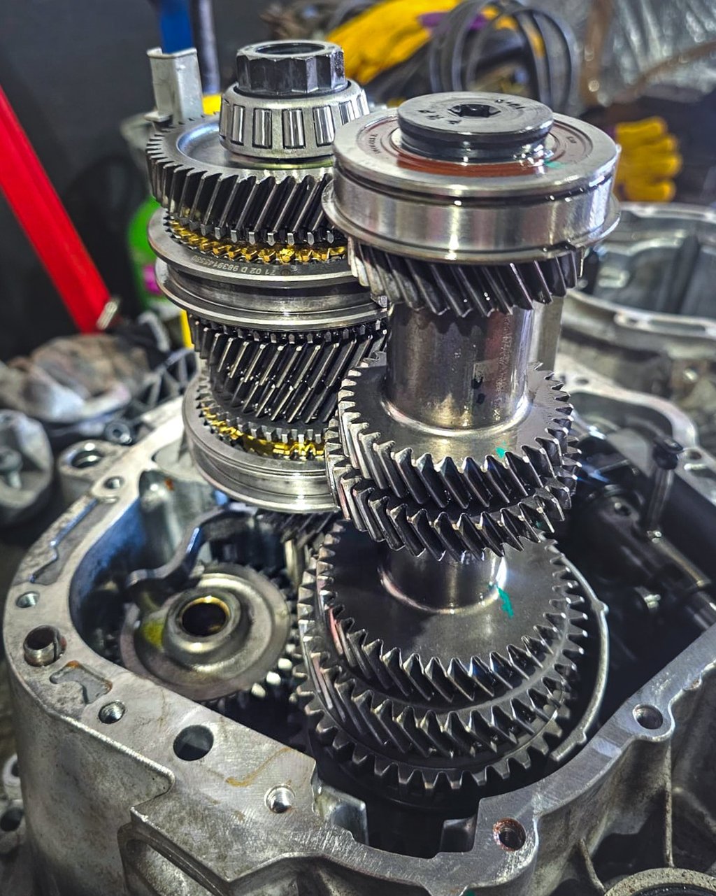 Internal view of a manual car transmission showing metal gears and shafts during a gearbox repair.
