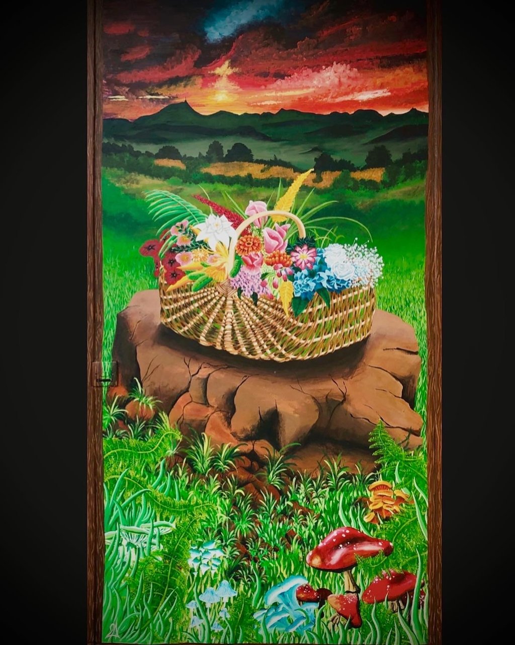 une peinture d'un panier en osier rempli de fleur devant un coucher de soleil