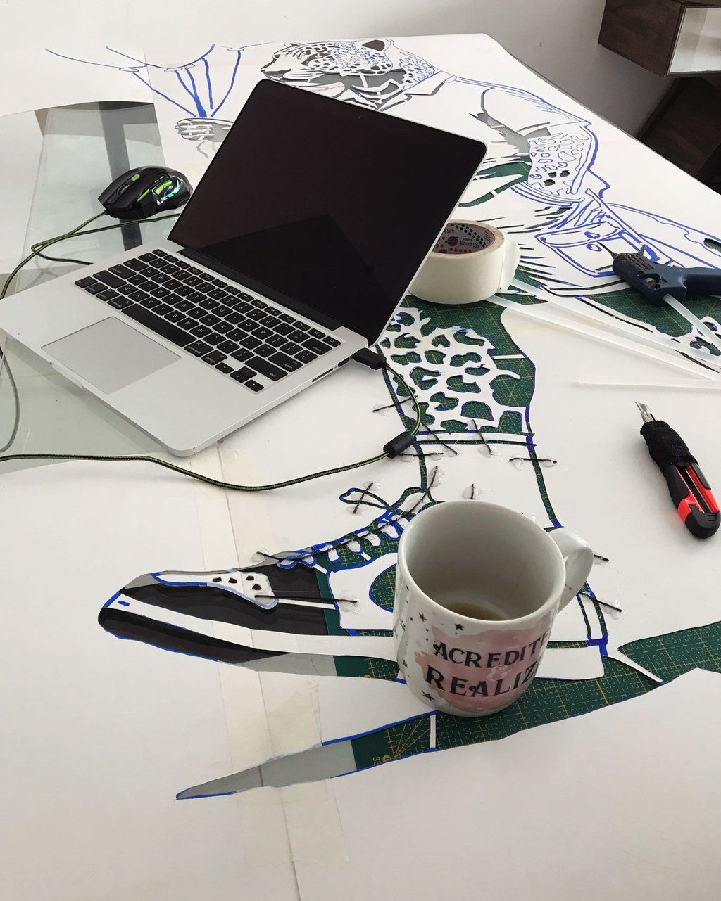 Cenário do ateliê com esboços espalhados pela mesa.