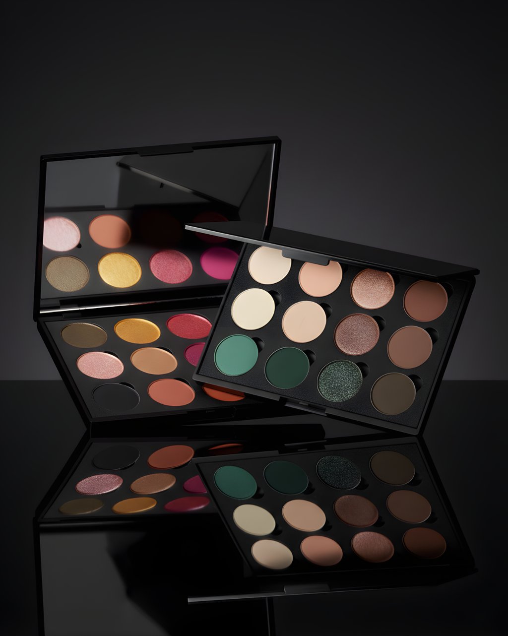 Two professional eyeshadow palettes with matte and shimmer shades reflecting on a dark surface.