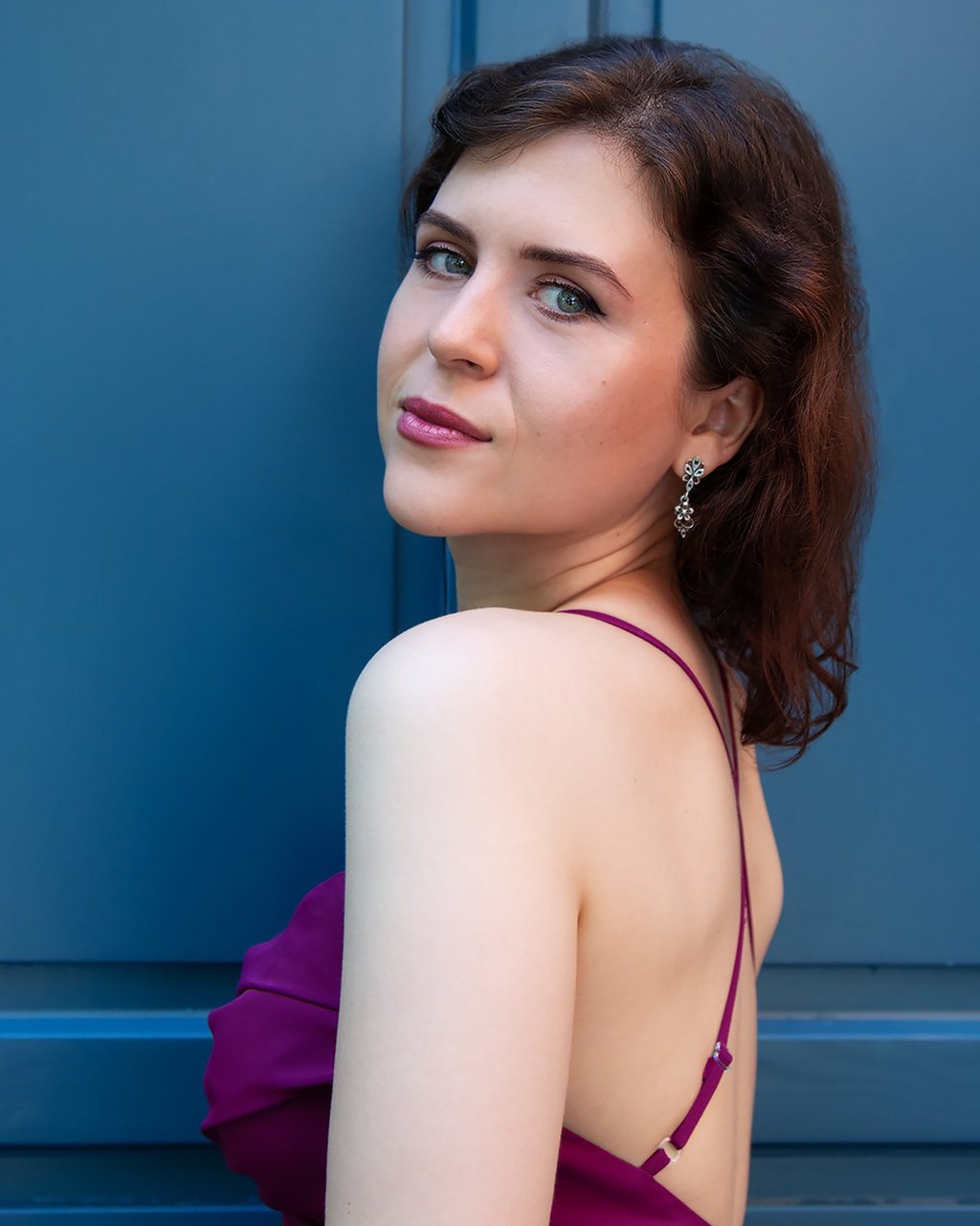 a woman in a purple dress standing in front of a blue door