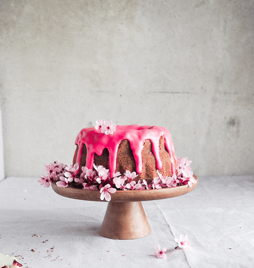 babka oblana różowym lukrem przystrojona kwiatami wiśni