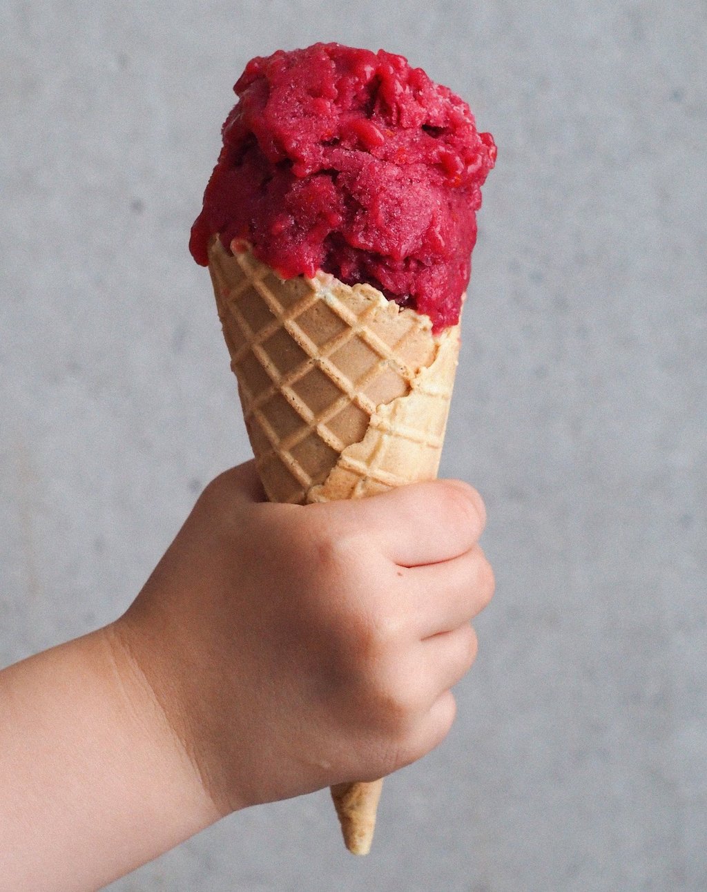 sorbet rabarbarowy w rożku trzymany przez dziecko