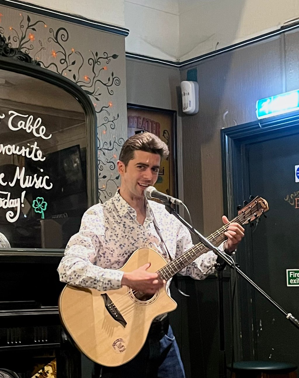 Olly Williams performing live at The Fiddler’s Elbow in Brighton, singing into a microphone while playing guitar on stage.