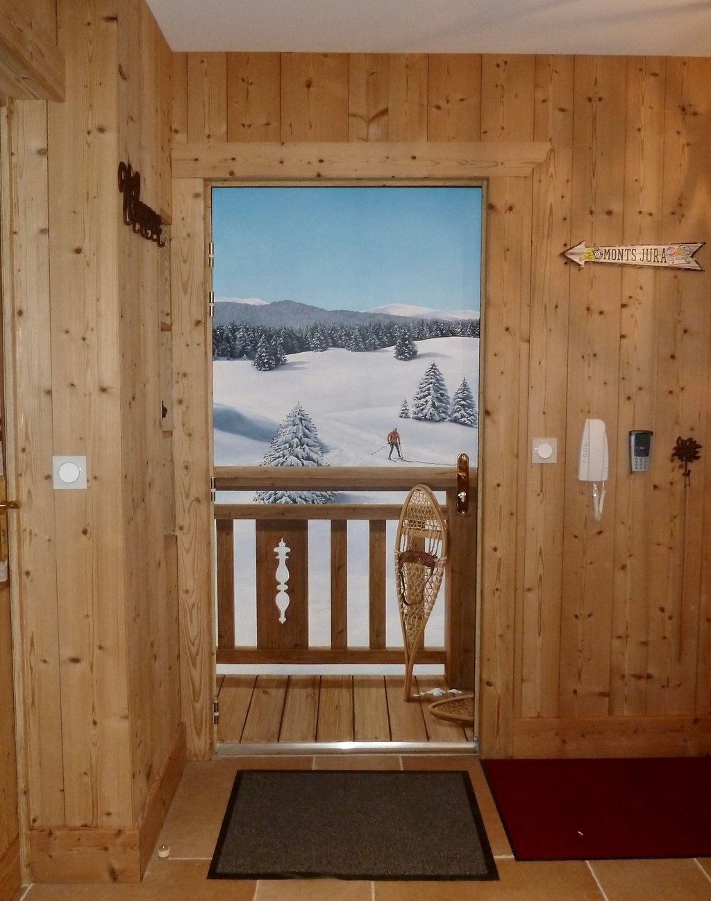 Trompe-l'oeil réalisé sur une porte d'entrée. Il représente un paysage enneigé avec barrière en bois