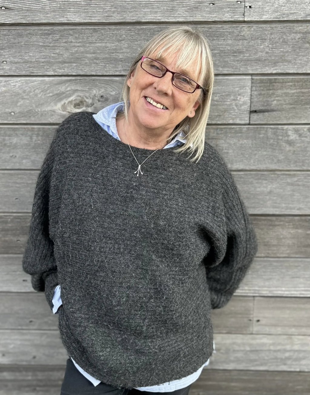 a woman in a gray sweater and glasses