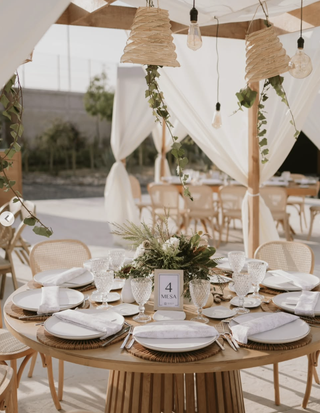 Mesa redonda decorada con vajilla blanca y detalles en madera.