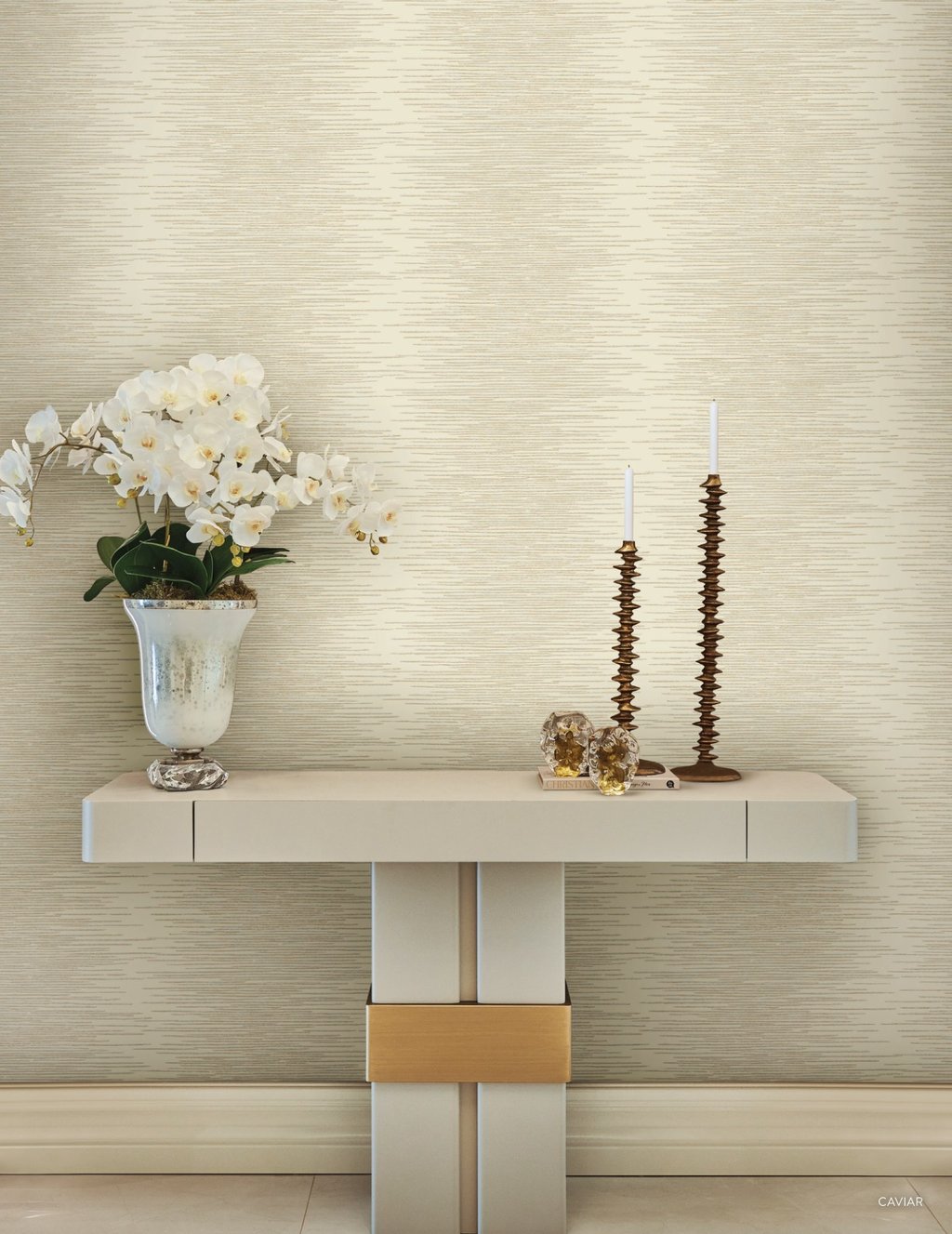 Elegant cream textured wallpaper behind a modern console table with white orchids and gold candle holders.