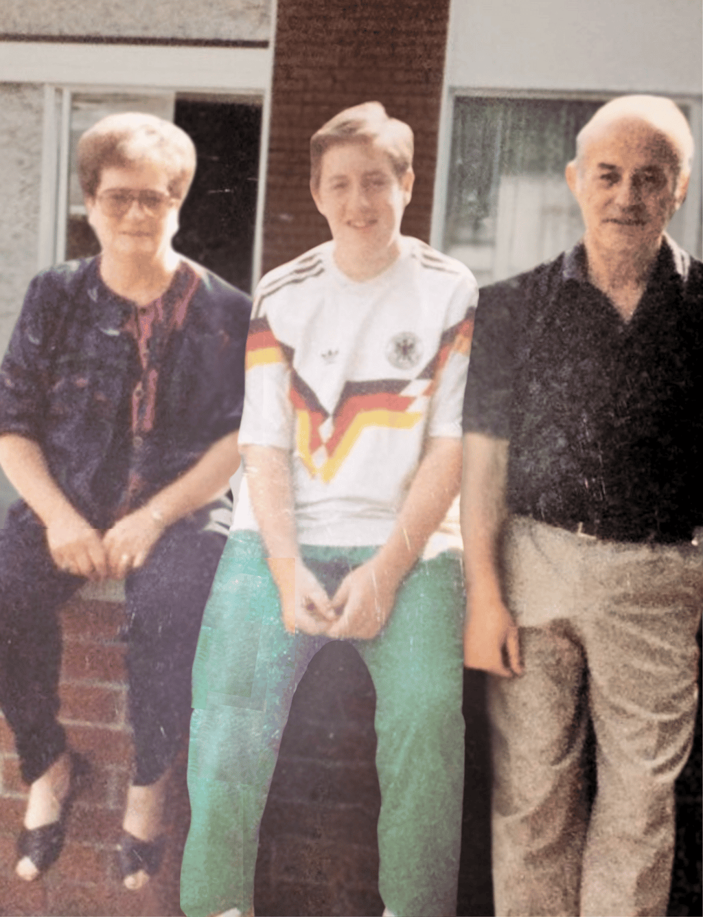 Vintage family photo of a boy in a German soccer jersey sitting with his grandparents outside.