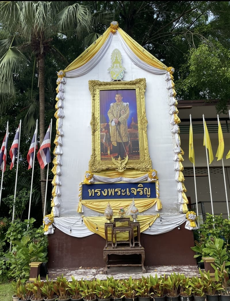 Goldgerahmtes Porträt des Königs von Thailand auf einem zeremoniellen Altar mit thailändischen Flagg