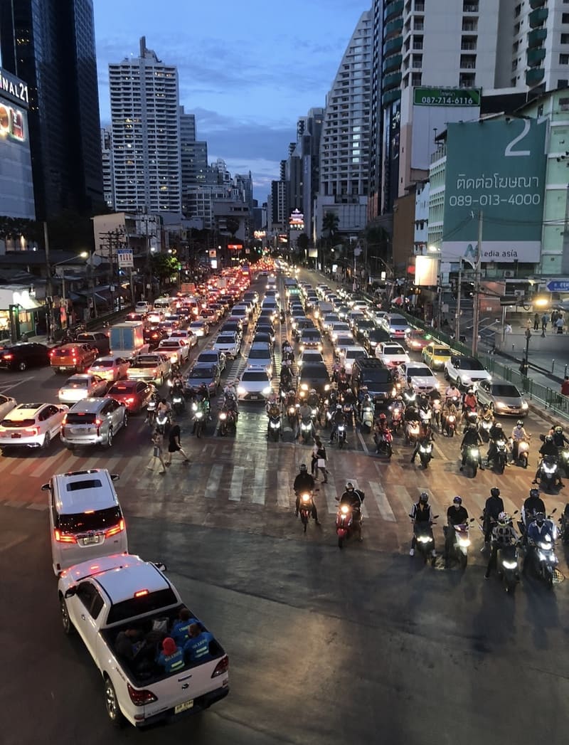 Starker Abendverkehr mit Autos und Motorrädern auf einer belebten Straße in Bangkok