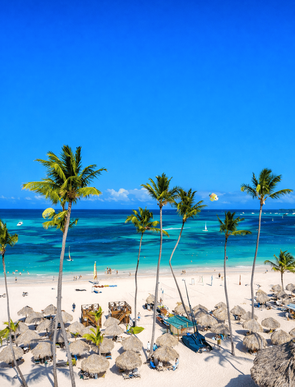 Palm trees and white sand beach at a Dominican Republic all inclusive resort with turquoise ocean and beach loungers