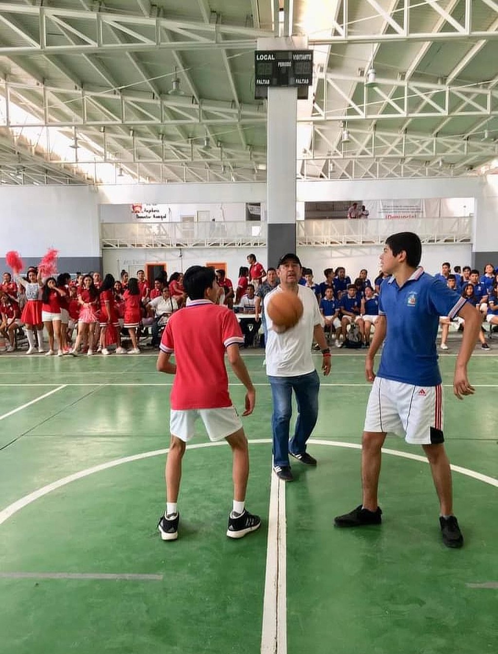 Alumnos jugando un partido de baloncesto en una competencia de rojos contra azules
