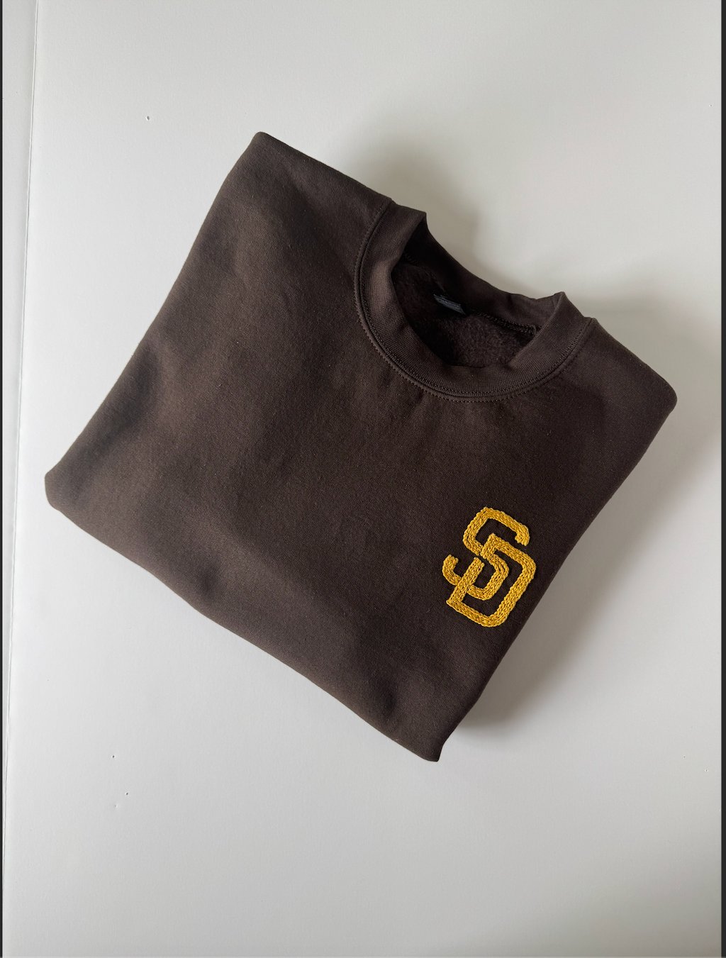 `a brown San Diego Padres sweatshirt with the SD logo embroidered in golden yellow