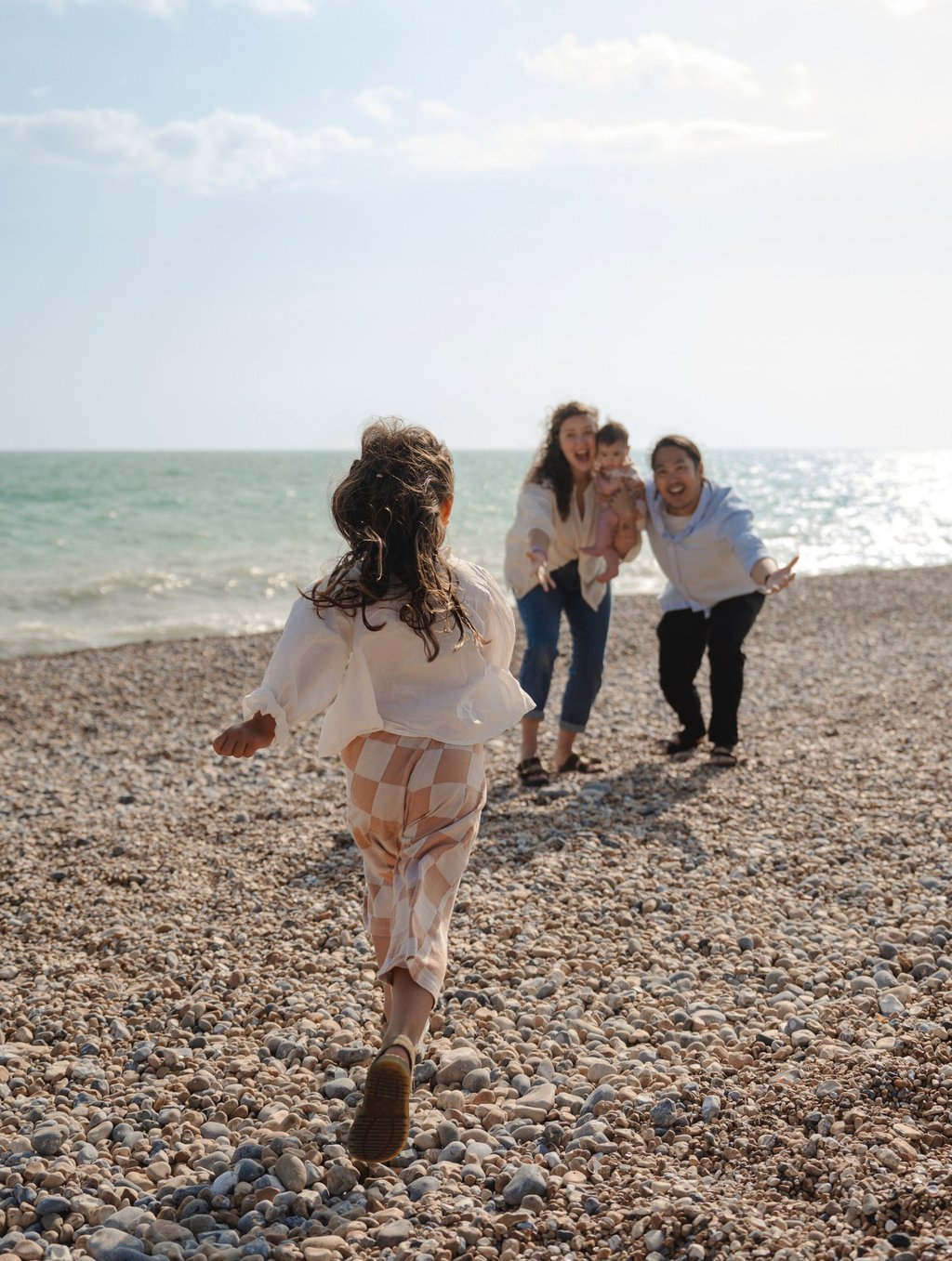Little girl running towards her parents on Brighton beach
