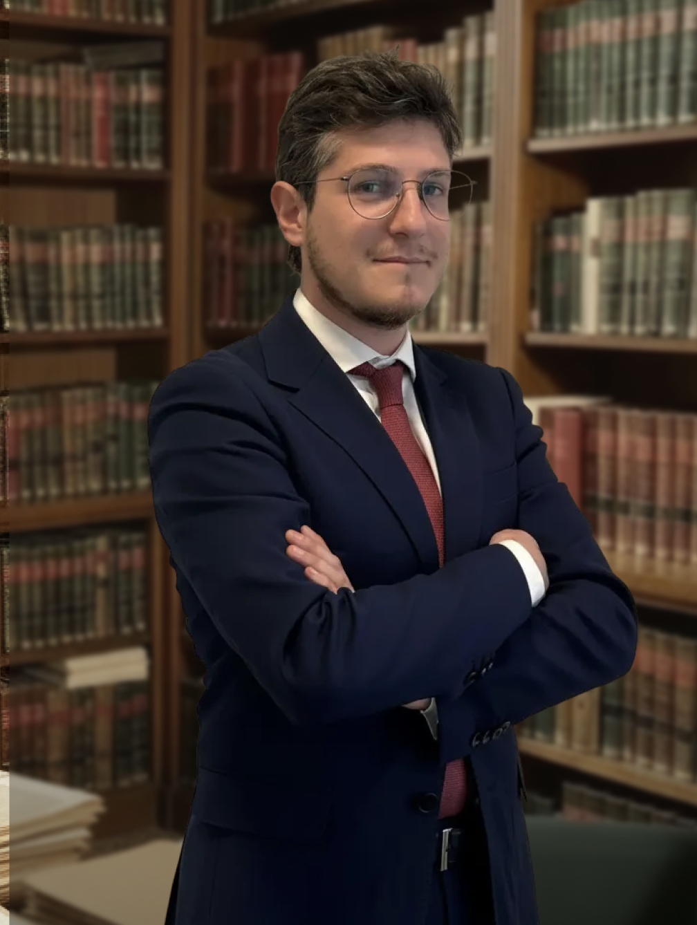 Professional male attorney in a navy suit standing with arms crossed in a legal library.