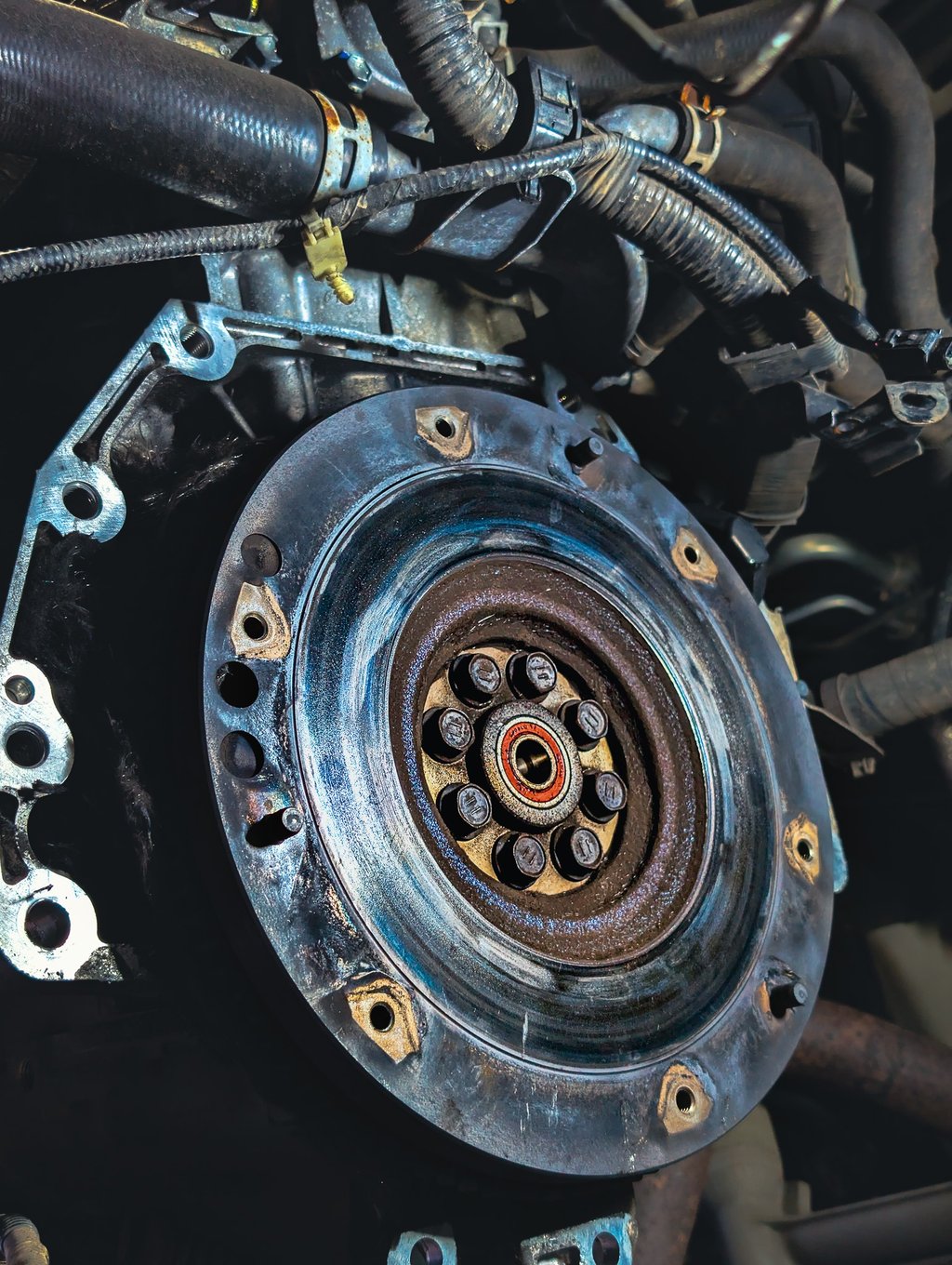 Close-up of a car flywheel and pilot bearing installed on an engine crankshaft during a clutch repair.