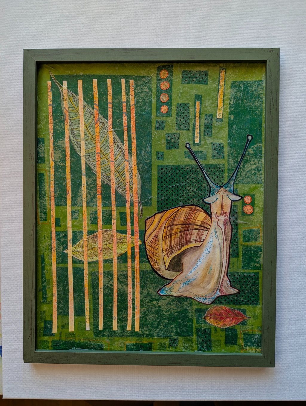 Green and orange playful mid-mod art of a helix snail in a green frame by Kathy LaFollett.