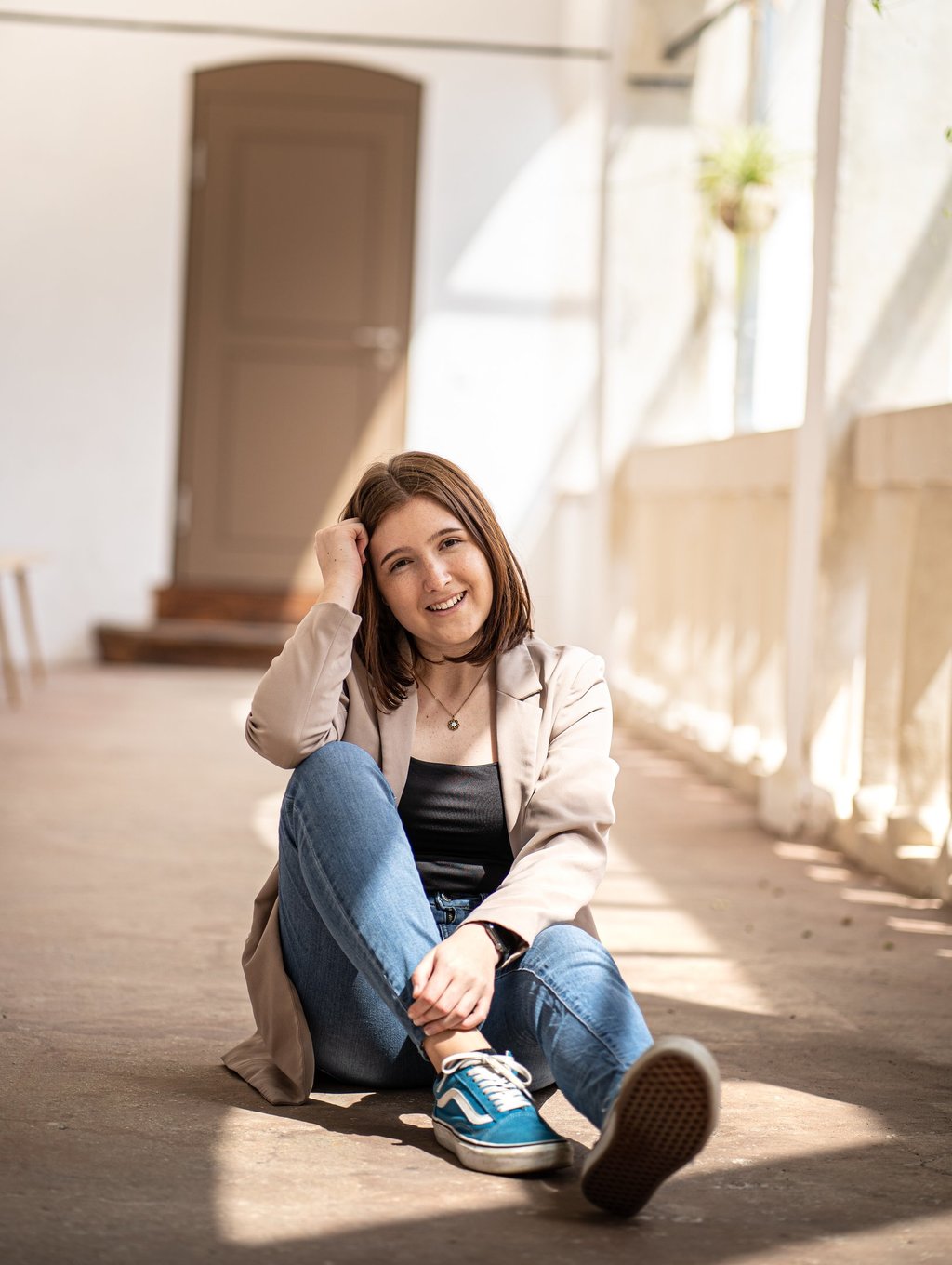Frau sitzt am Boden in einer lockeren Position und schaut nett in die Kamera
