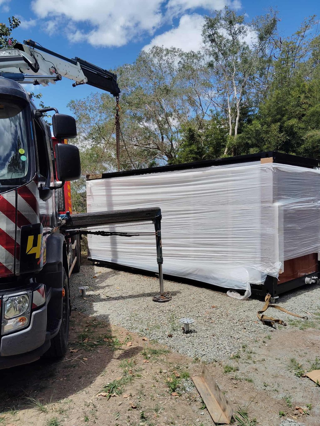Livraison d'une maison modulaire préfabriquée par camion avec grue.