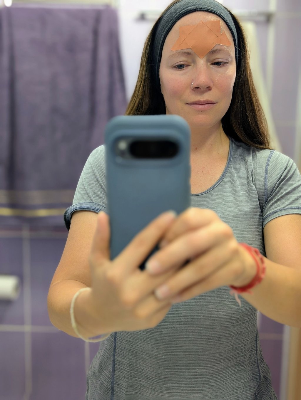 Samantha taking a mirror selfie using Frownies forehead wrinkle patches for anti-aging skincare.