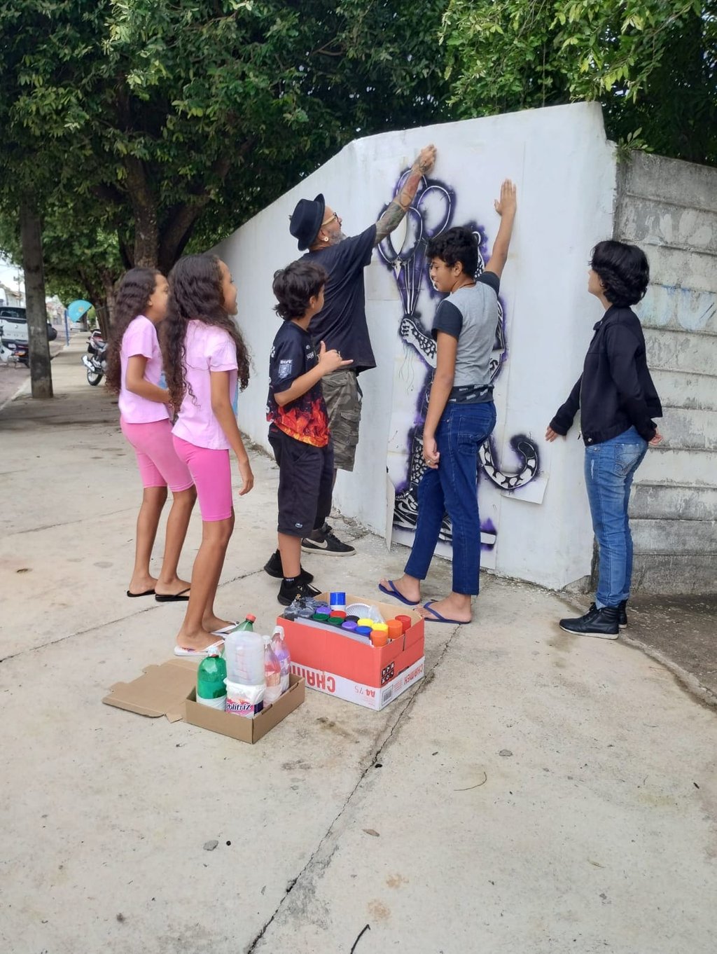 Jovem aplicando stencil – Estudante pratica a aplicação de stencil em uma parede da escola.