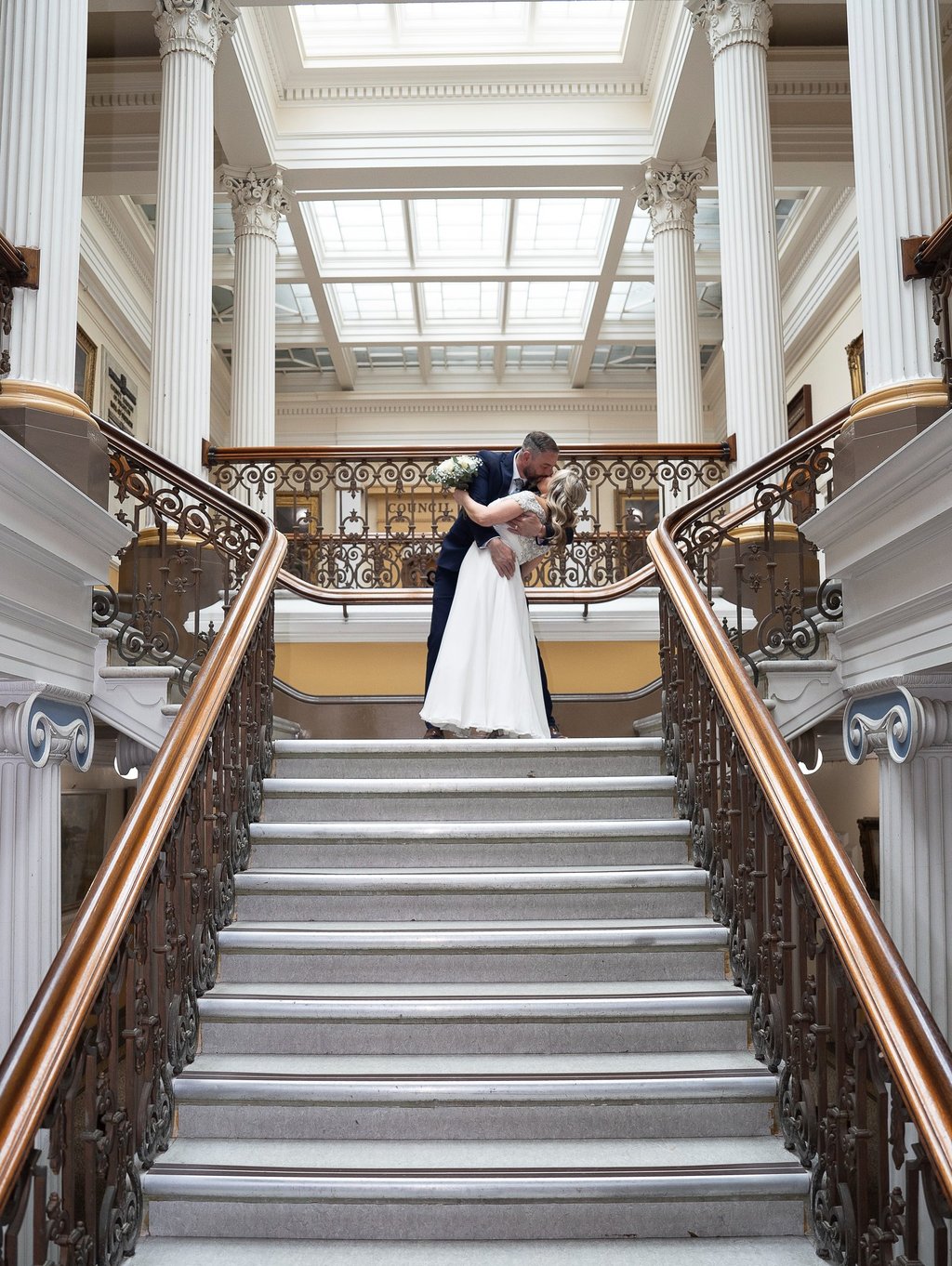 Bride and groom kissing on grand staircase wedding venue, Brighton UK