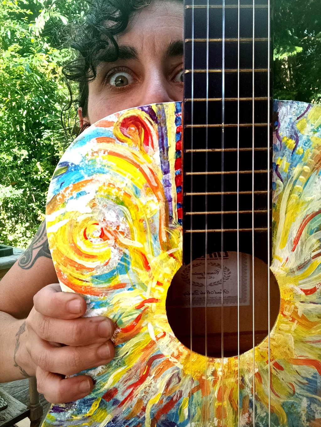 Naia qui tient Suun - une peinture sur guitare très colorée