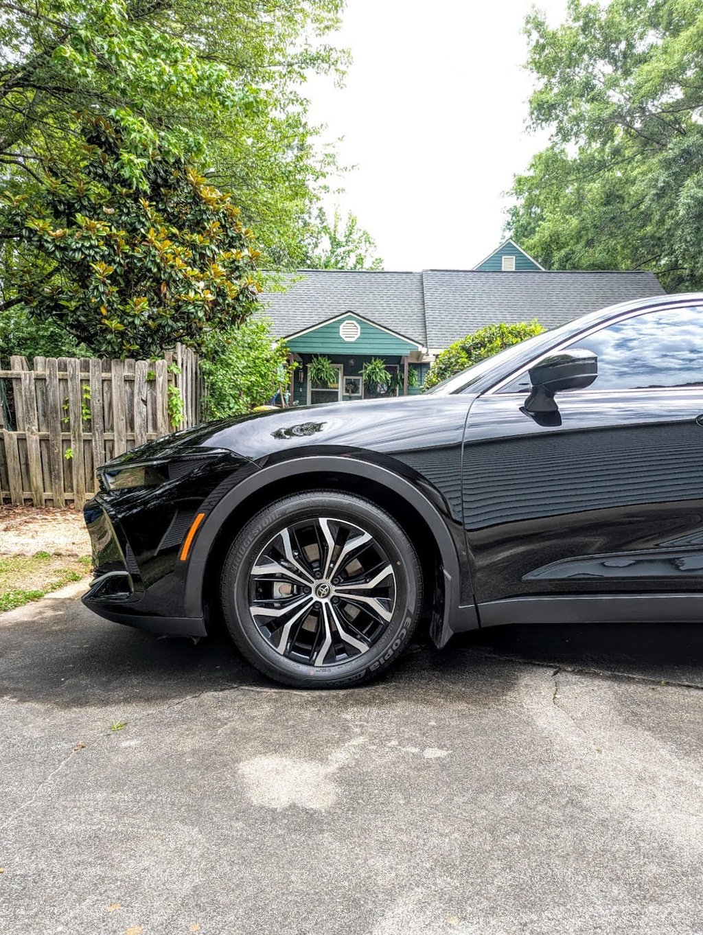 Side view of a black Toyota Crown featuring sleek alloy wheels parked in a driveway.