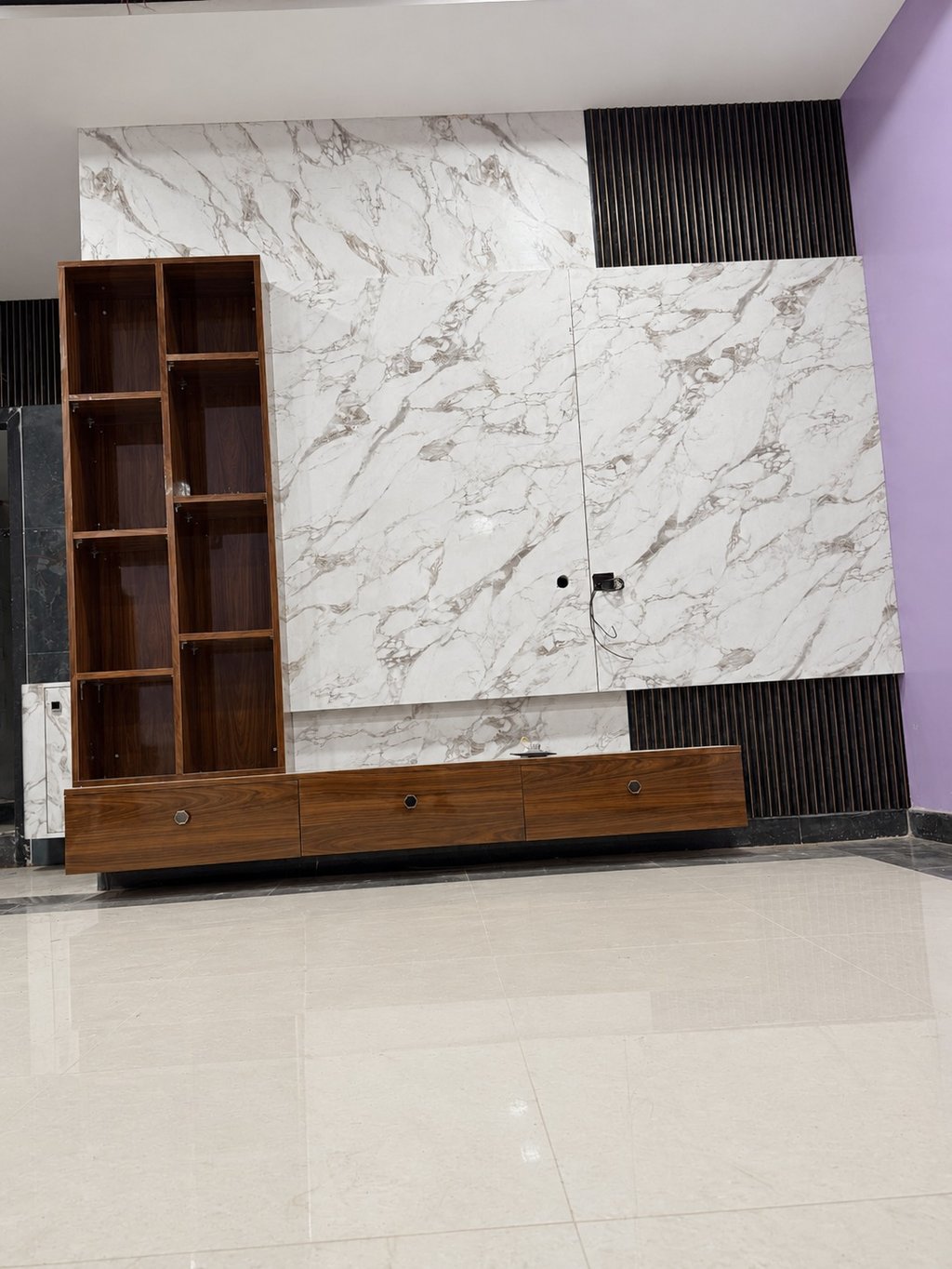 Modern marble wall TV unit with wooden cabinets and slatted panels for living room interior design.