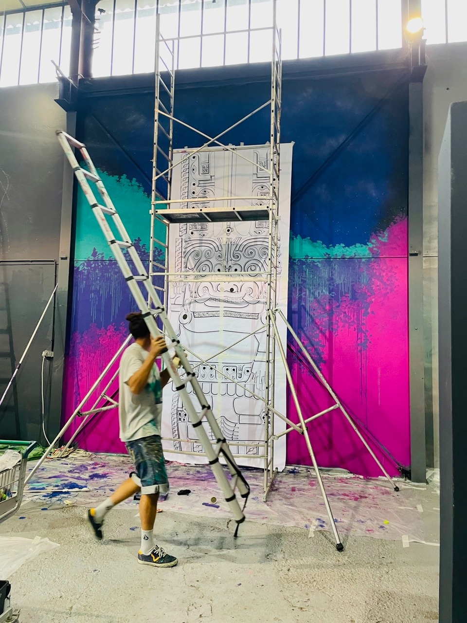 un homme qui porte une échelle devant une fresque en cour de création