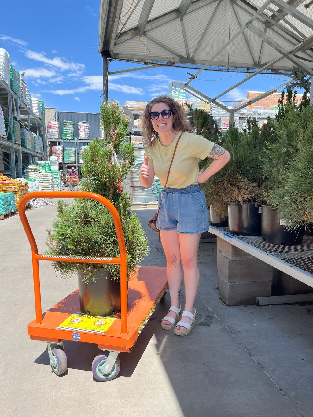 a woman in a yellow shirt is holding a plant tattoo artist being silly