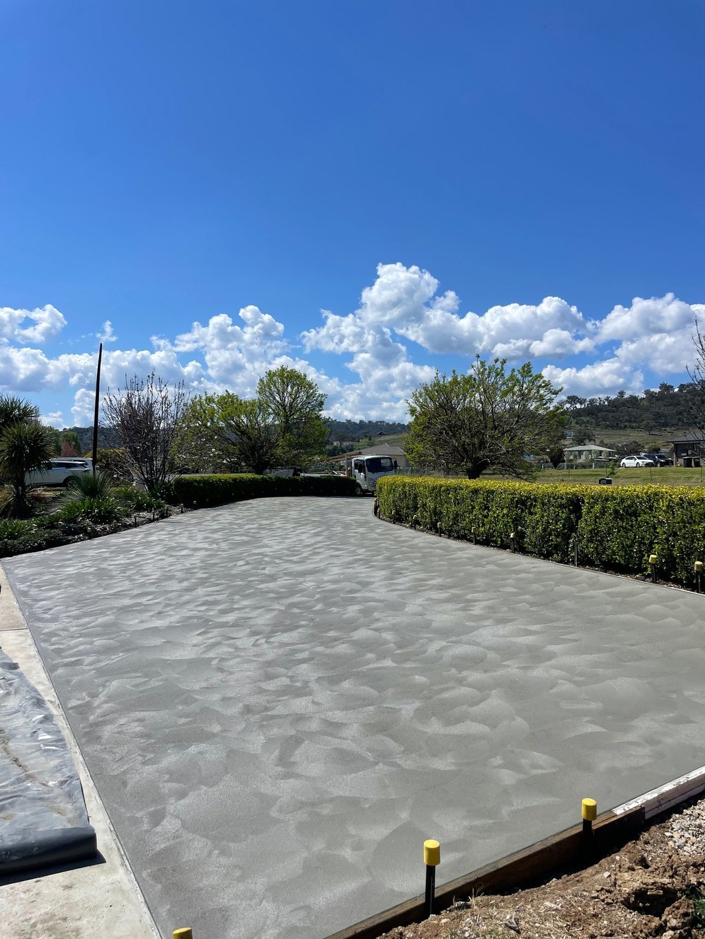 Freshly poured decorative concrete driveway with hand-troweled swirl finish in a residential landscape.