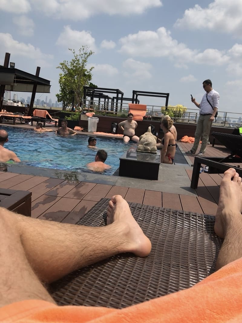 Gäste entspannen am Rooftop-Pool eines Luxushotels mit Blick auf die Skyline und Sonnenliegen