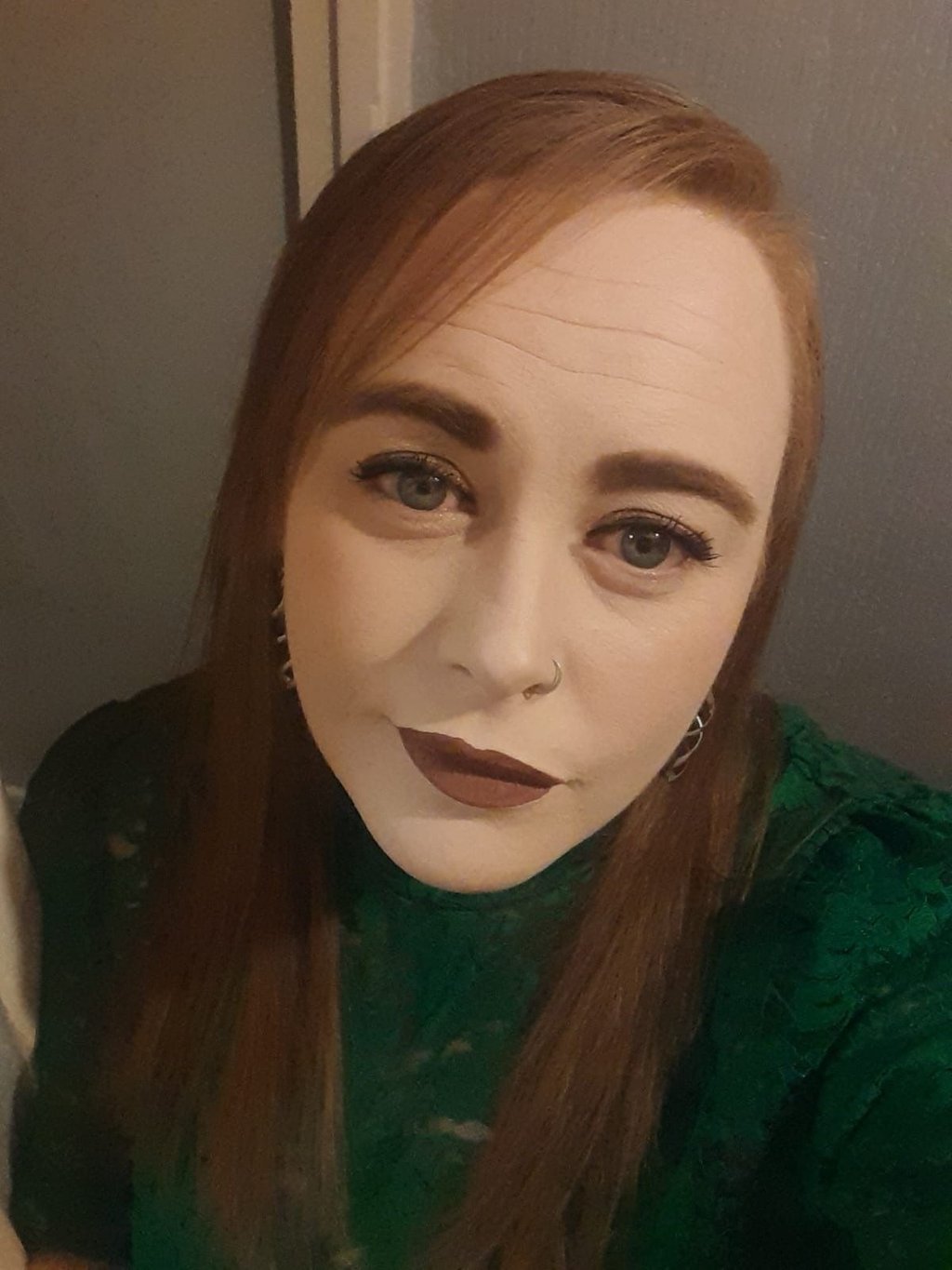 Nicola, wearing a green lace top and dark lipstick.