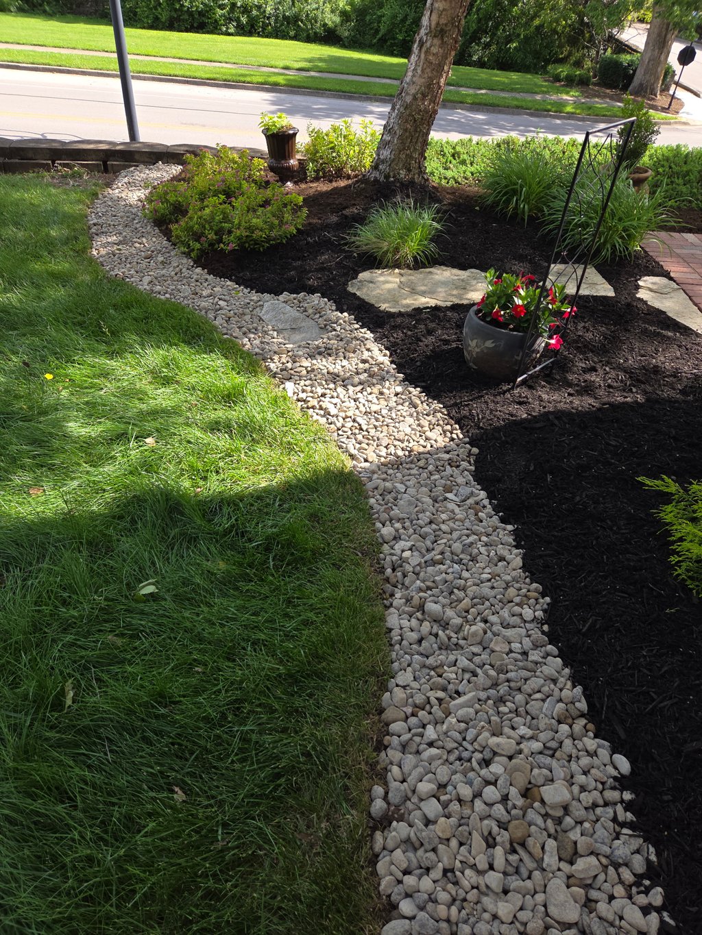 Decorative rock border edging around landscaped garden bed with plants