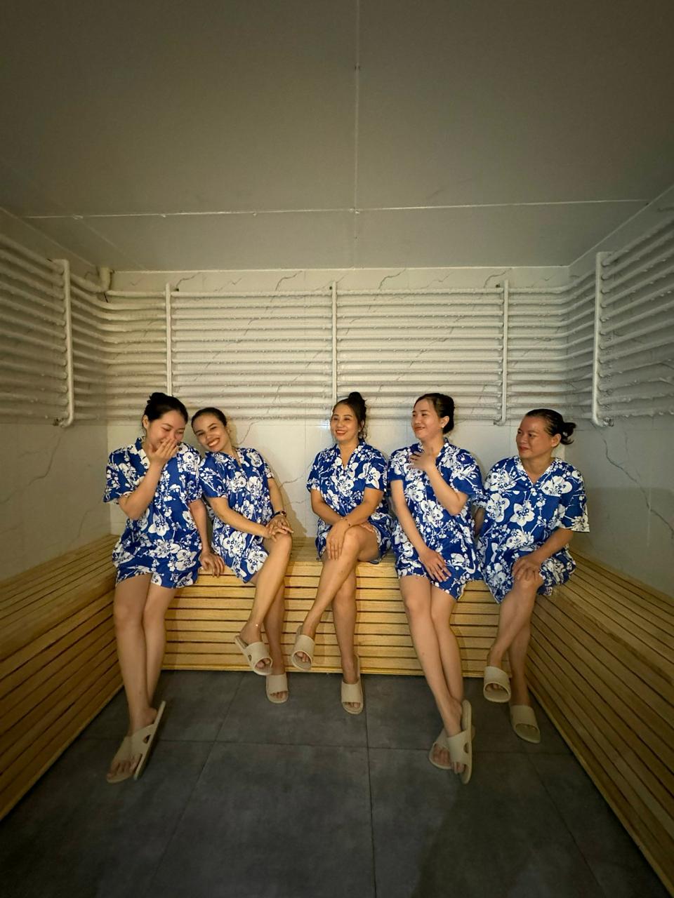 a group of women in blue dresses sitting on a bench ina cold room