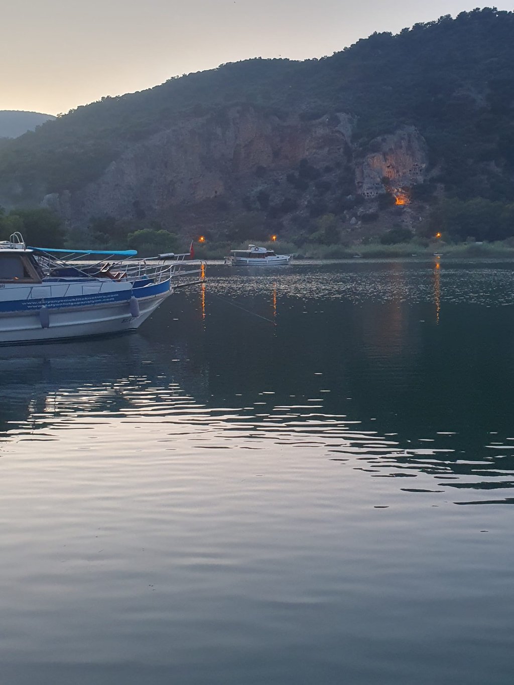 a boat is docked in a lake with a mountain in the background