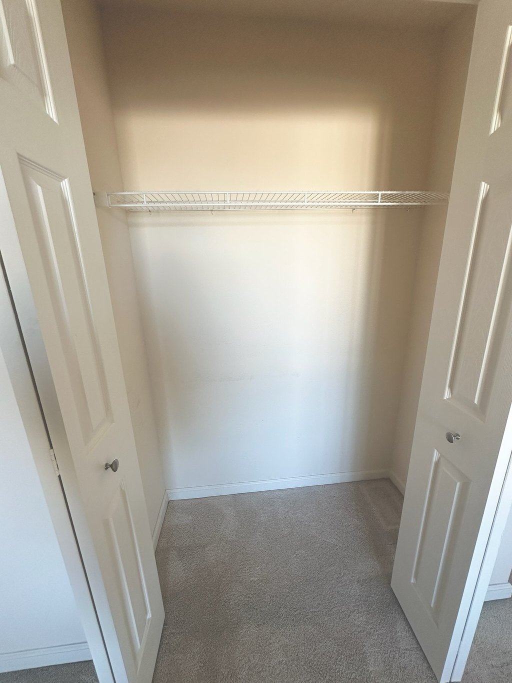 an empty closet with a closet door open and a closet with a shelf