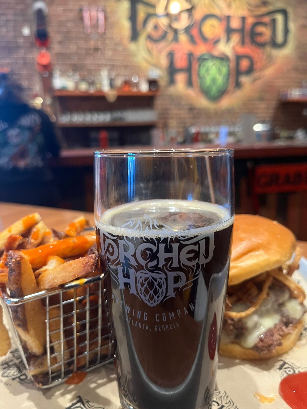 A glass of dark craft beer, French fries, and a burger at Torched Hop Brewing Company in Atlanta.